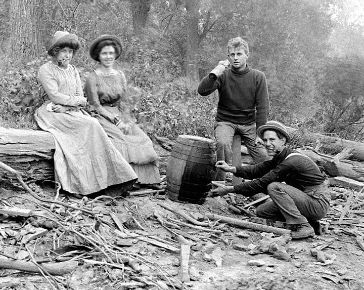 Two couples appear to be having a smoking and drinking party on the beach, ca. 1905